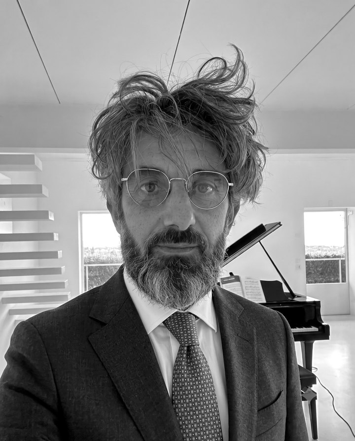 Ritratto in bianco e nero di Francesco Mariano, pianoforte a coda sullo sfondo